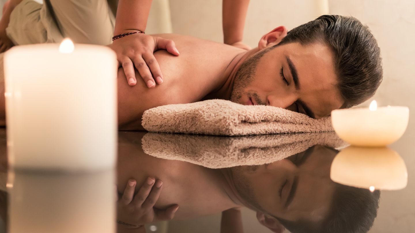 Man receiving a relaxing remedial massage in a serene setting with candles, reflecting a calm therapeutic experience.